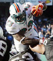 Ronnie Brown jumps in the end zone from the 1-yard line for a TD while being defended by three Raiders. (AP Photo/Marcio Jose Sanchez)